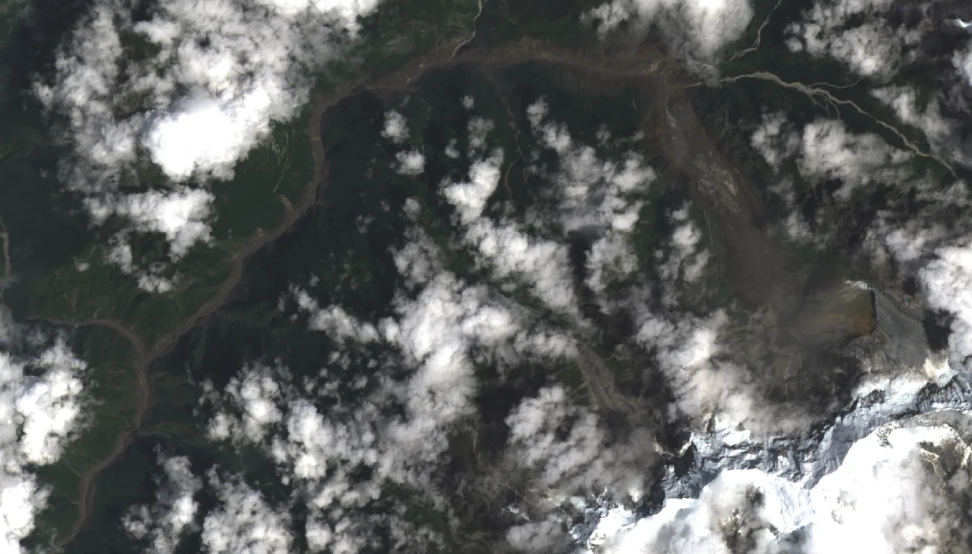 Landsat 9 satellite view of the flood aftermath: sediment-choked river channels and fresh debris scars cutting through the valley, under broken monsoon cloud.